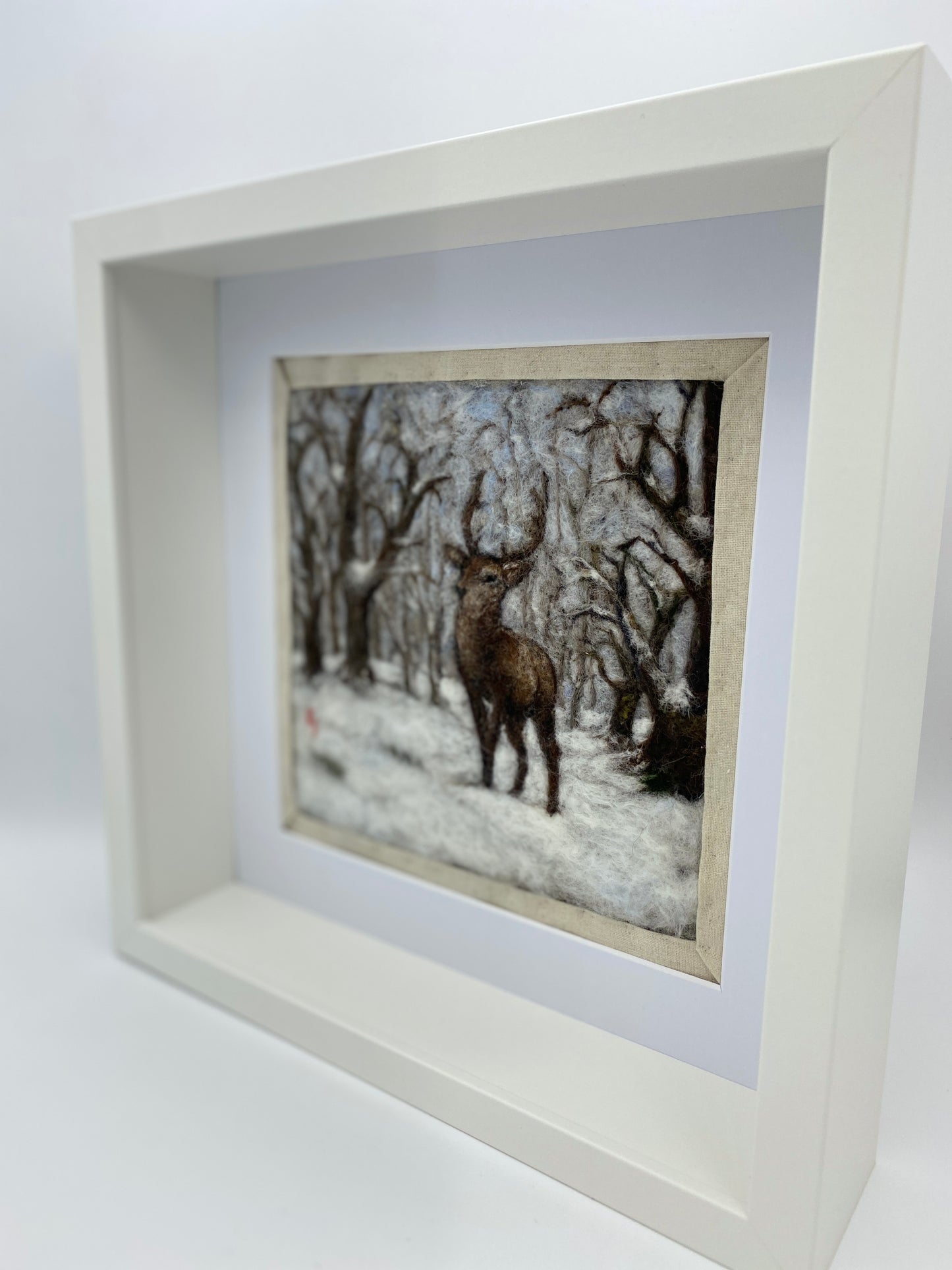 needle felted framed picture of a stag standing in woodland which is covered with fresh snow