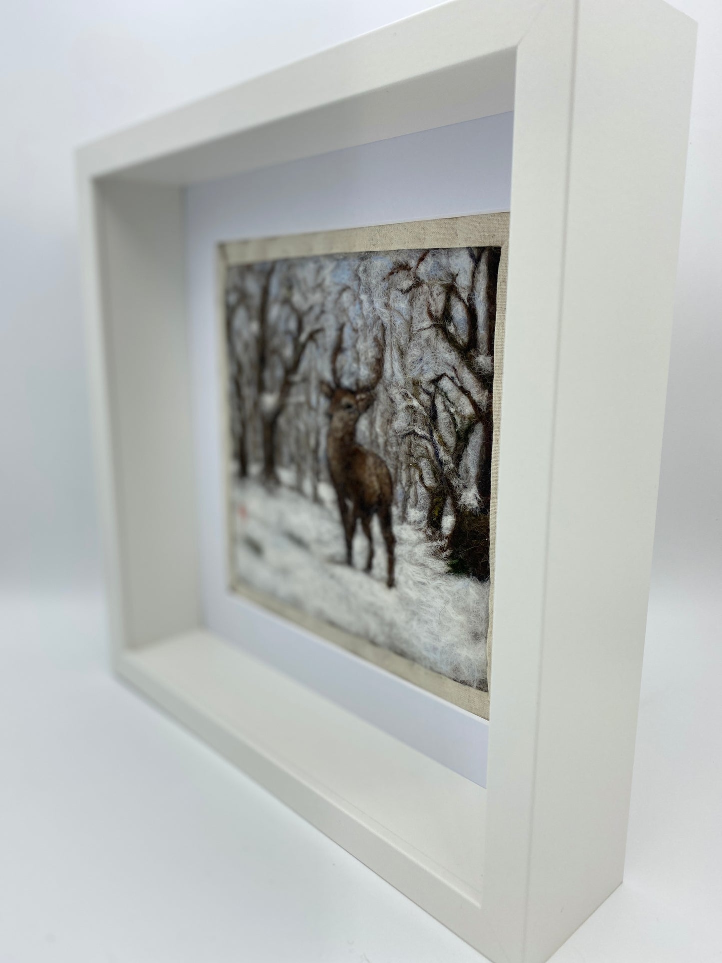 needle felted framed picture of a stag standing in woodland which is covered with fresh snow