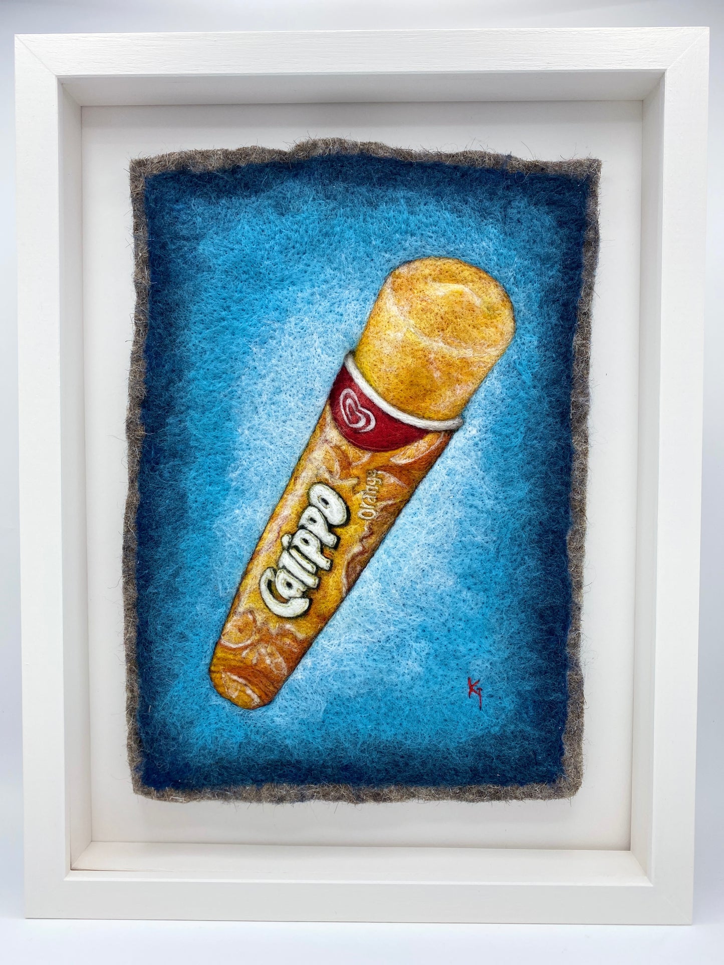 a white box framed needle felted study of an orange flavoured Calippo ice lolly on a blue background