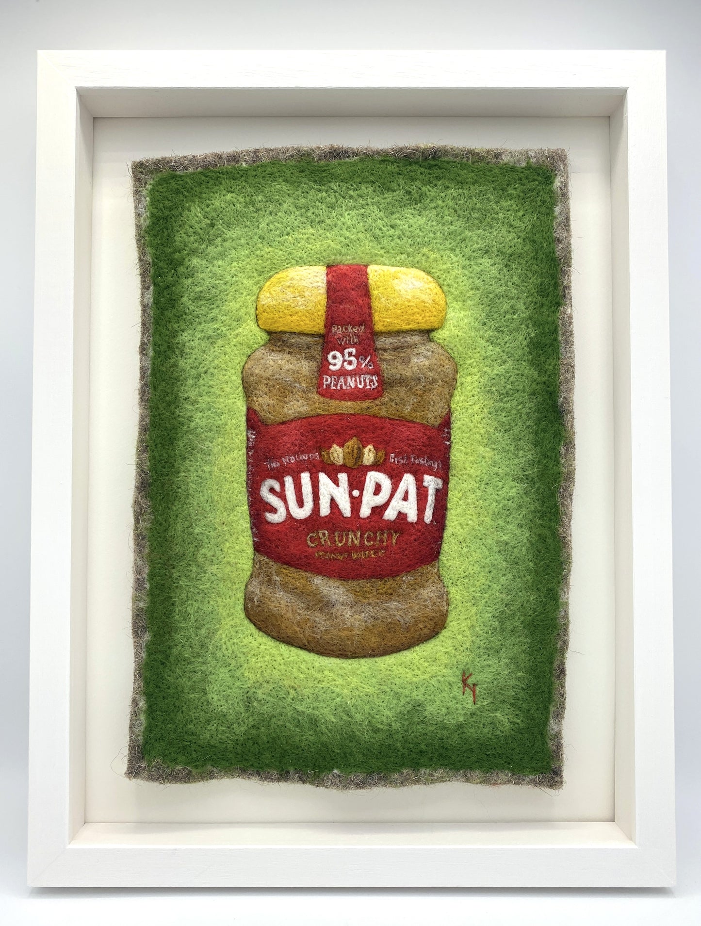 needle felted study of a jar of Sun-Pat peanut butter on a bright green background and framed in a white wooden box frame