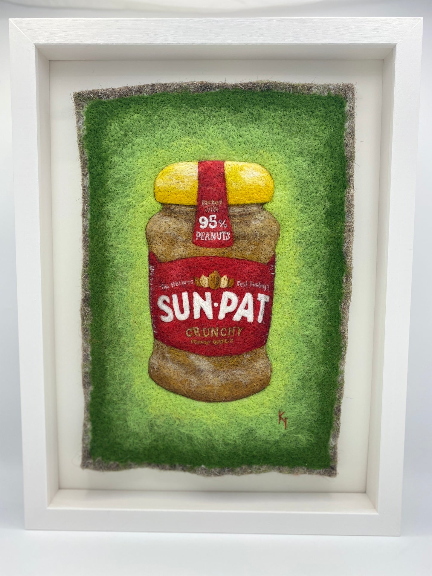 needle felted study of a jar of Sun-Pat peanut butter on a bright green background and framed in a white wooden box frame