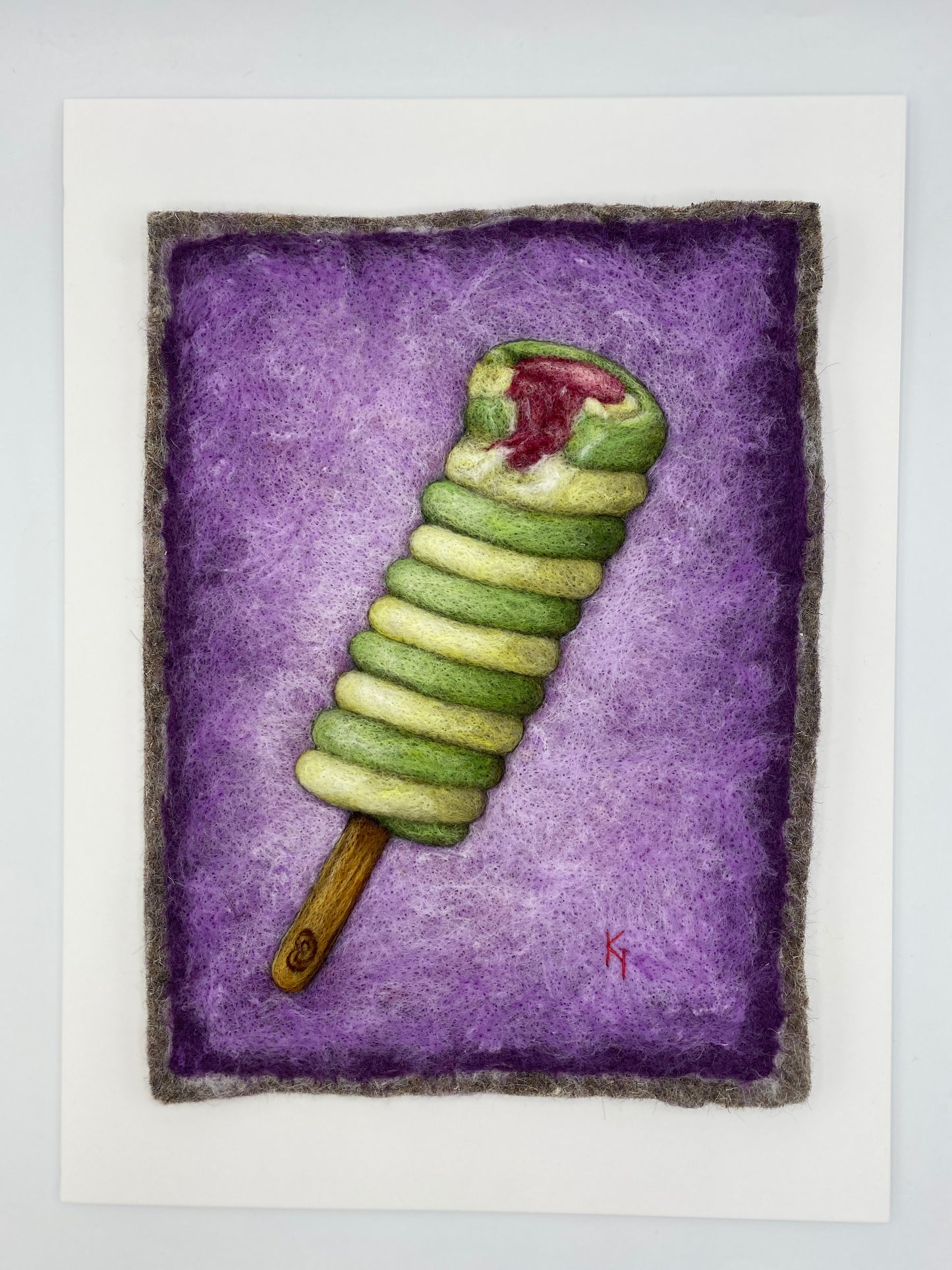 needle felted picture of a Twister ice lolly in green and yellow on a purple background