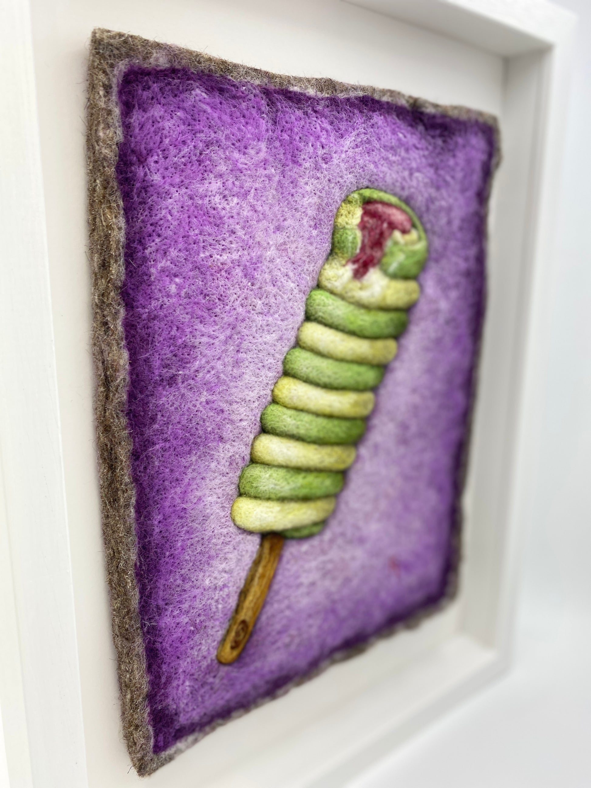 needle felted picture of a Twister ice lolly in green and yellow on a purple background