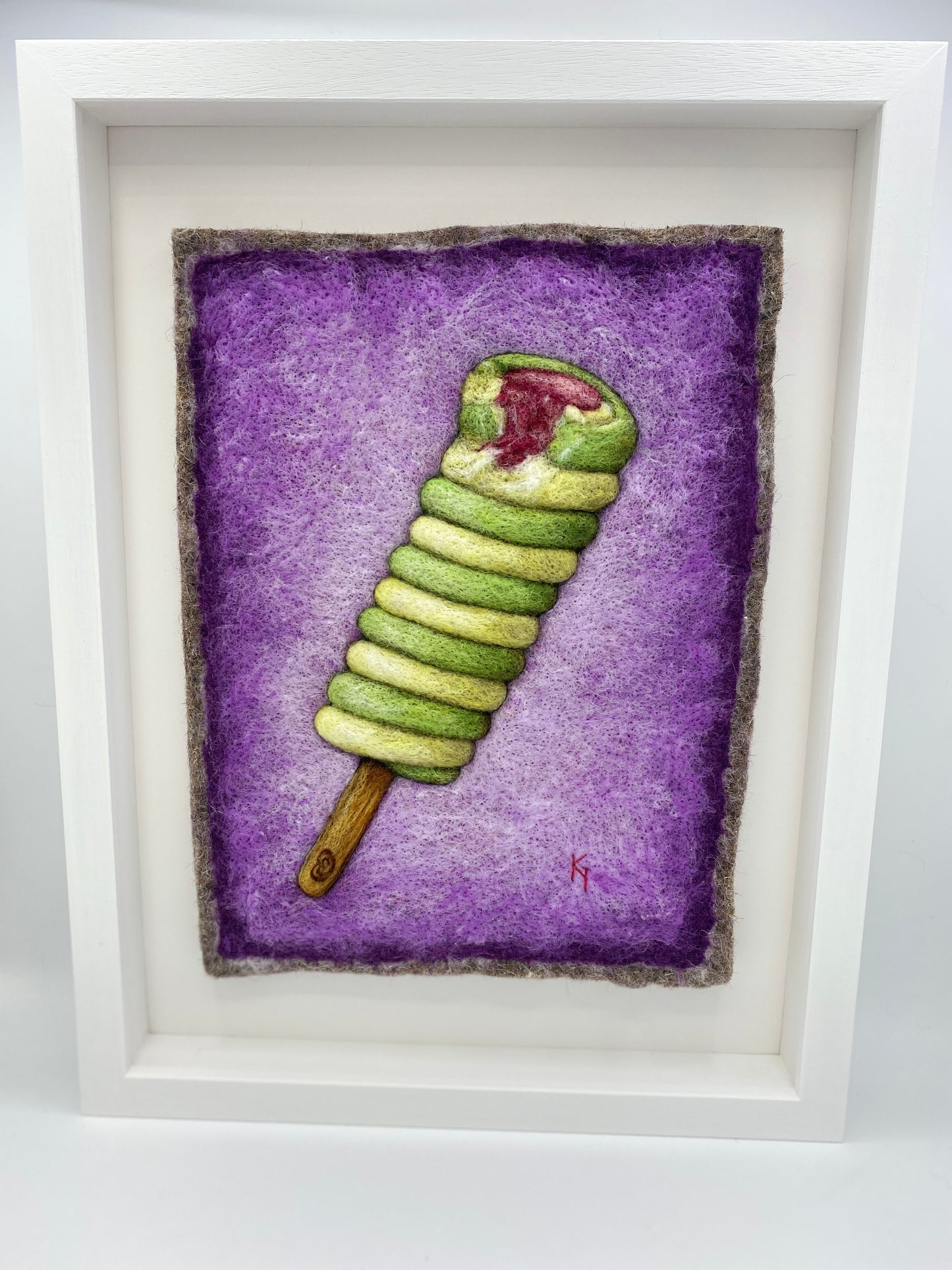needle felted picture of a Twister ice lolly in green and yellow on a purple background