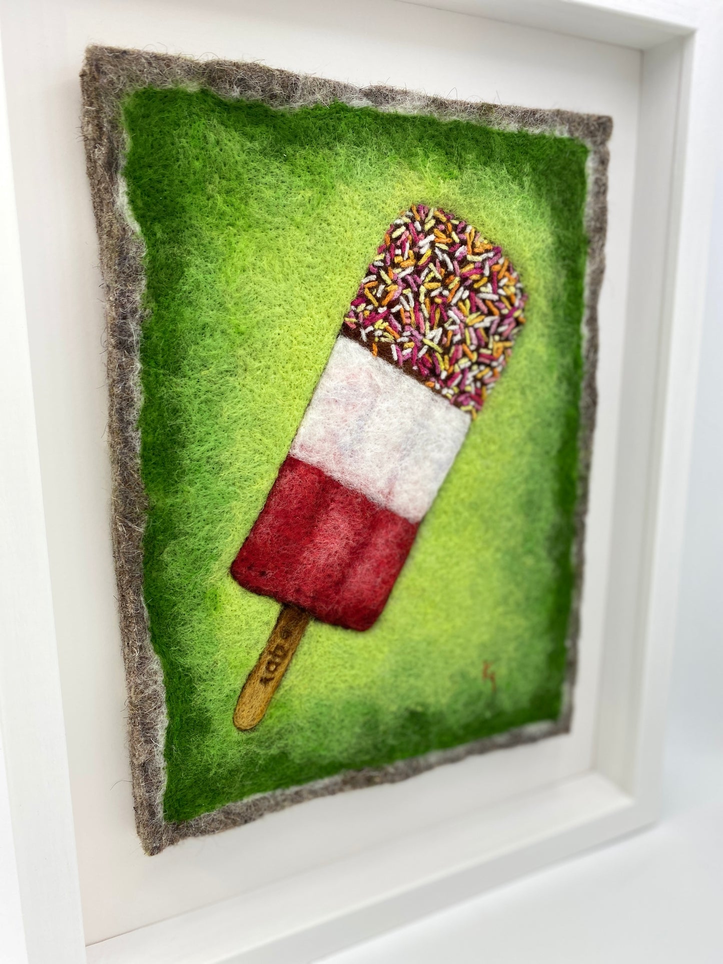 needle felted picture of a Fab ice lolly on a bright green background