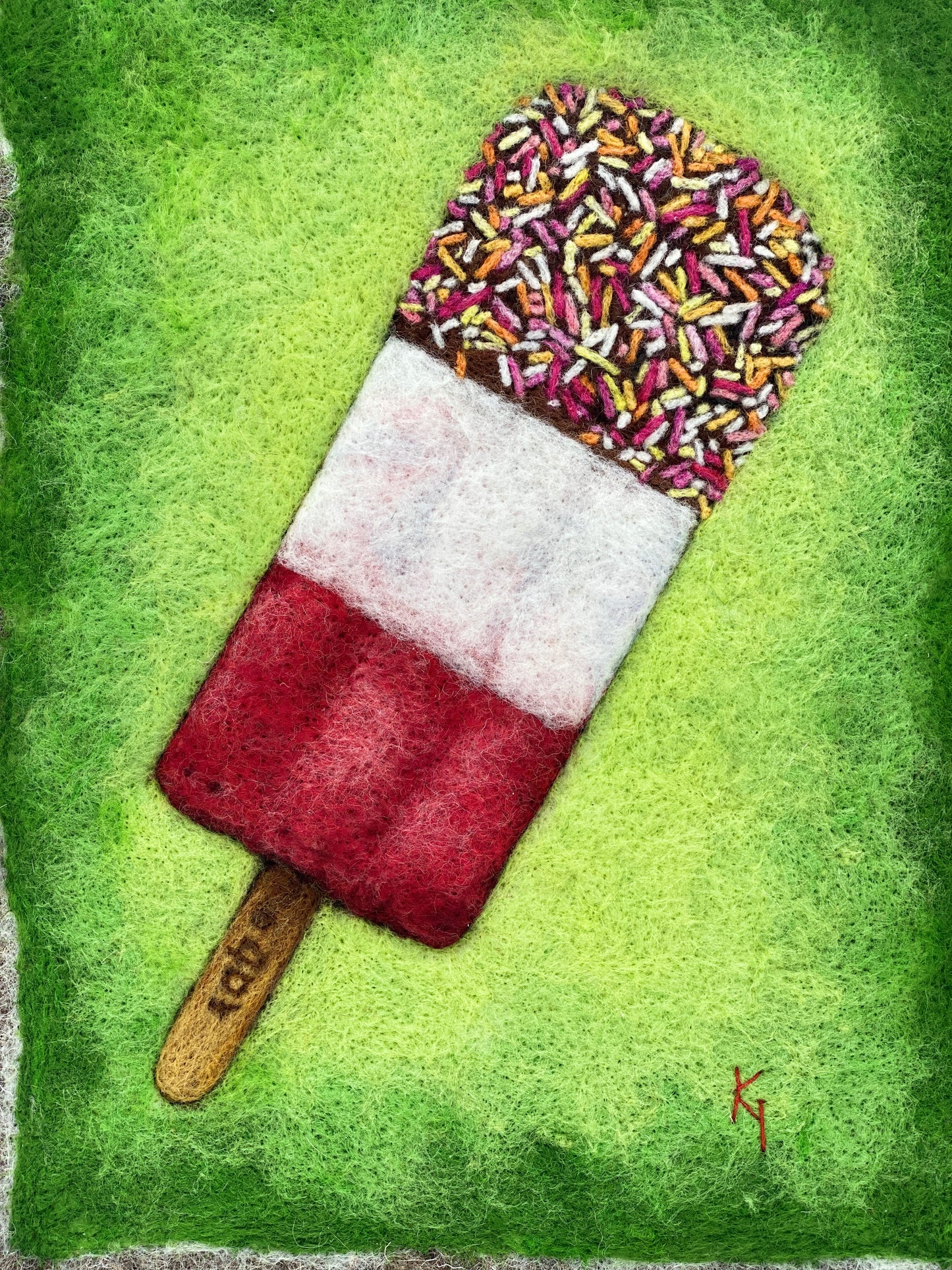 needle felted picture of a Fab ice lolly on a bright green background