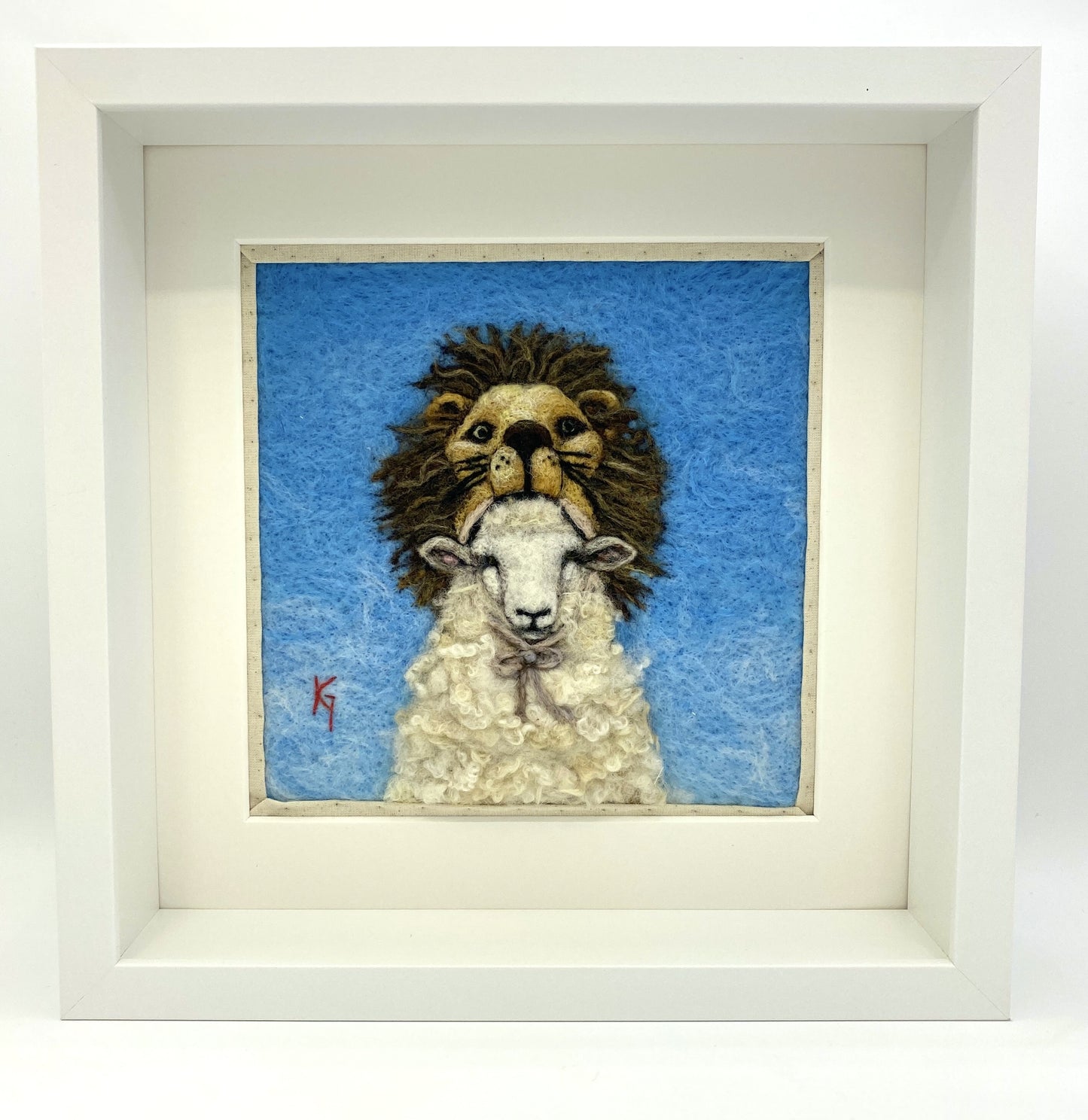 Needle felted framed depiction of a sheep with a lion headdress, with a blue background