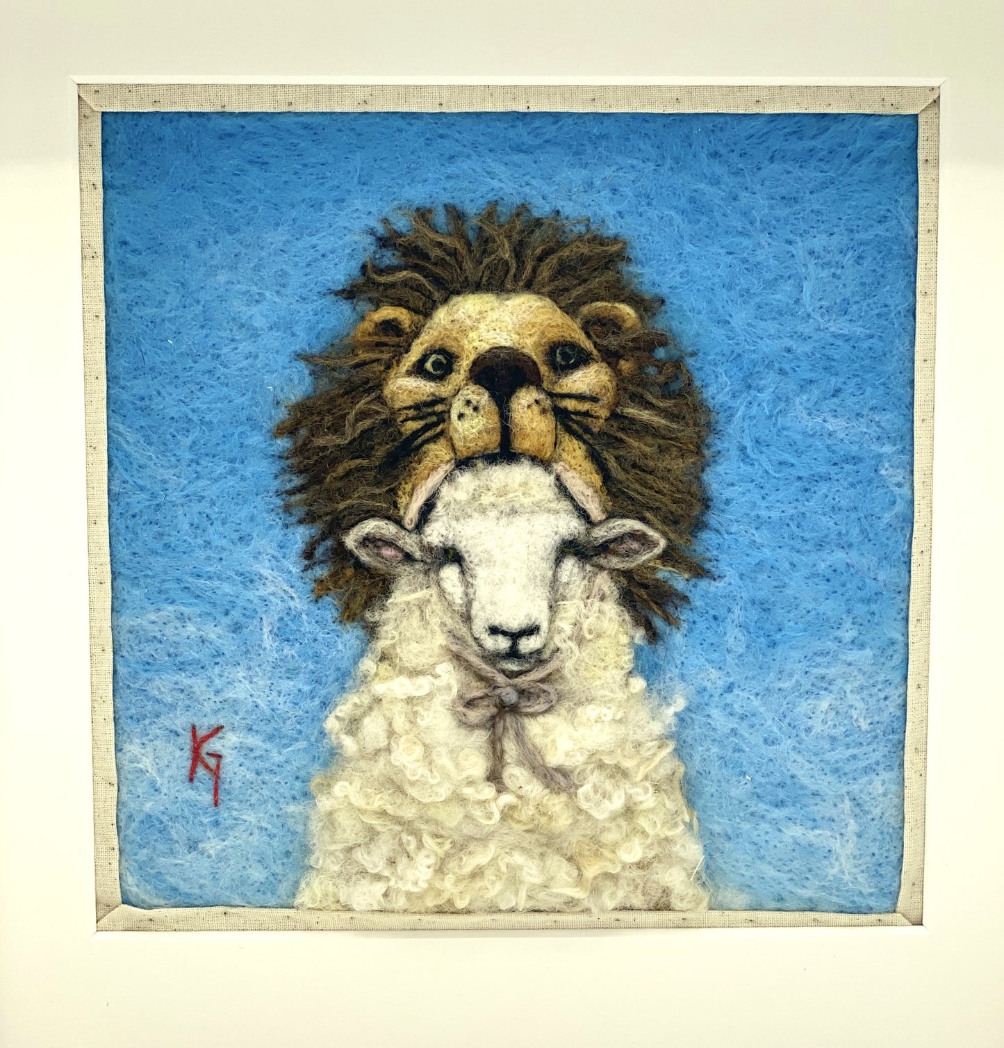 Needle felted framed depiction of a sheep with a lion headdress, with a blue background