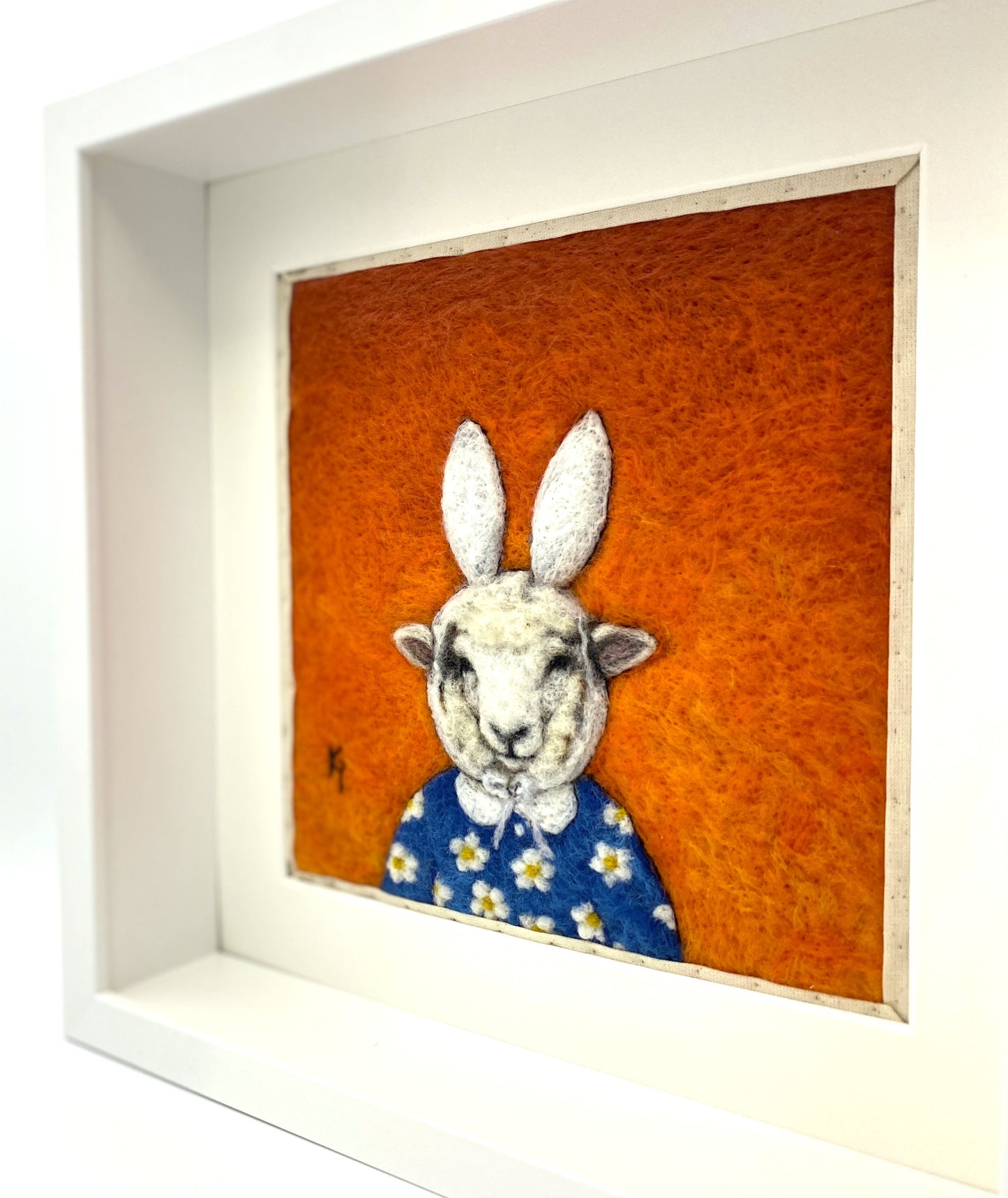 Needle felted picture of a sheep dressed as Miffy in her birthday dress, with an orange background