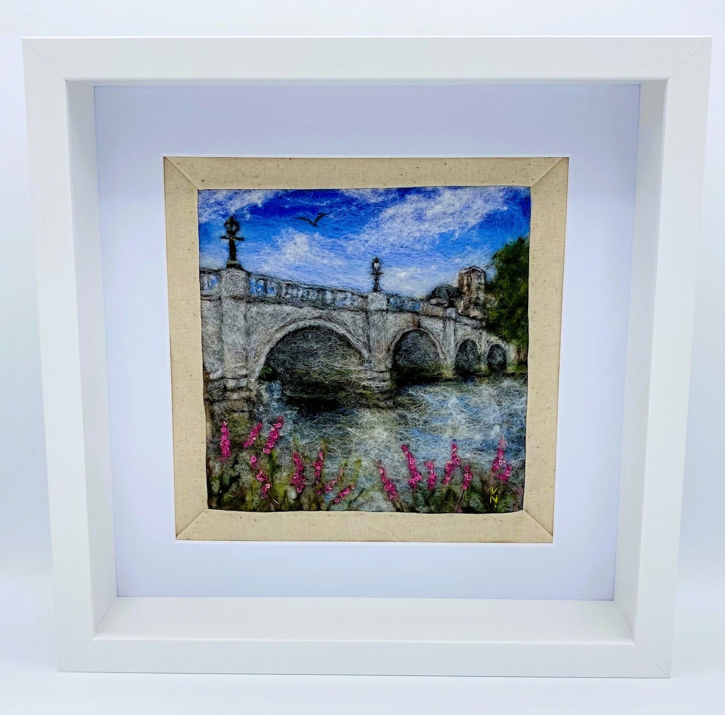 a box-framed, needle felted wool fibre picture of Ricmond Bridge showing the bridge, buildings across the river, trees, lamp posts and embroidered purple wild flowers