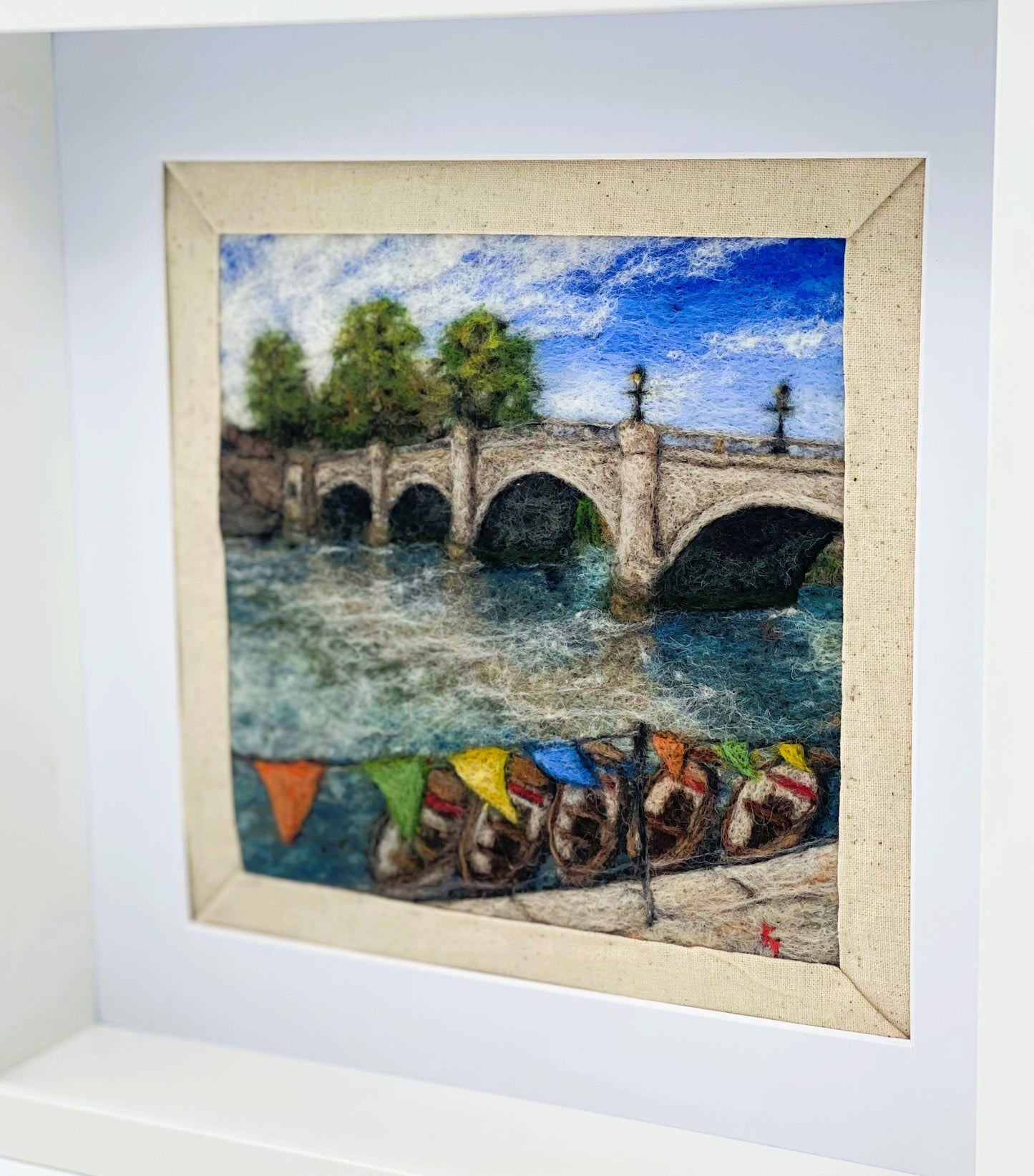 a box-framed, needle felted wool fibre picture of Ricmond Bridge showing the boats moared on the river, the bridge, trees, lamp posts and colourful bunting