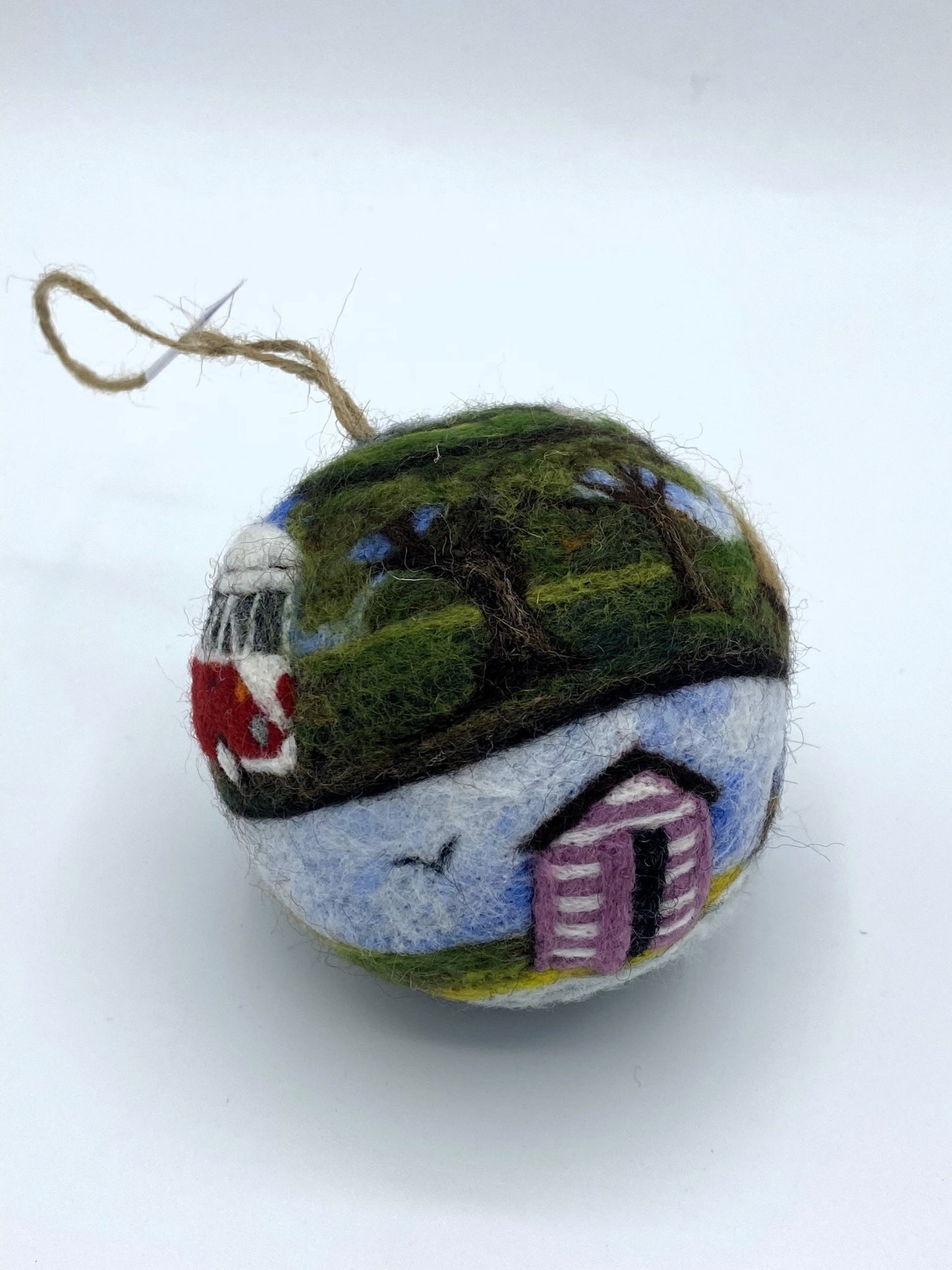 needle felted bauble depicting a camper van travelling through mountains, camping site and countryside and finally reaching the beach hut by the sea