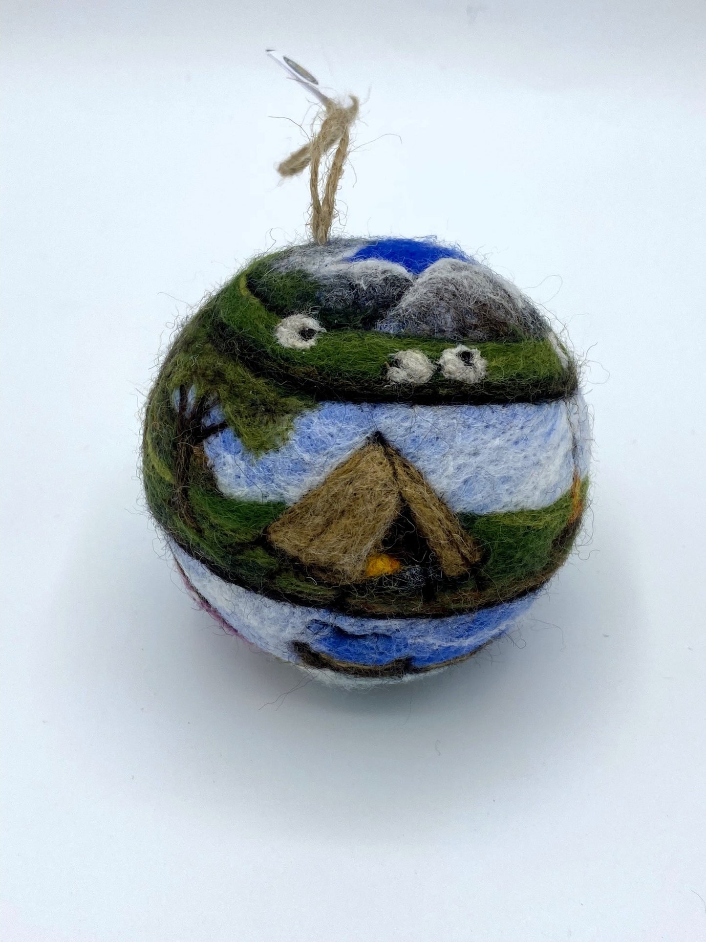 needle felted bauble depicting a camper van travelling through mountains, camping site and countryside and finally reaching the beach hut by the sea