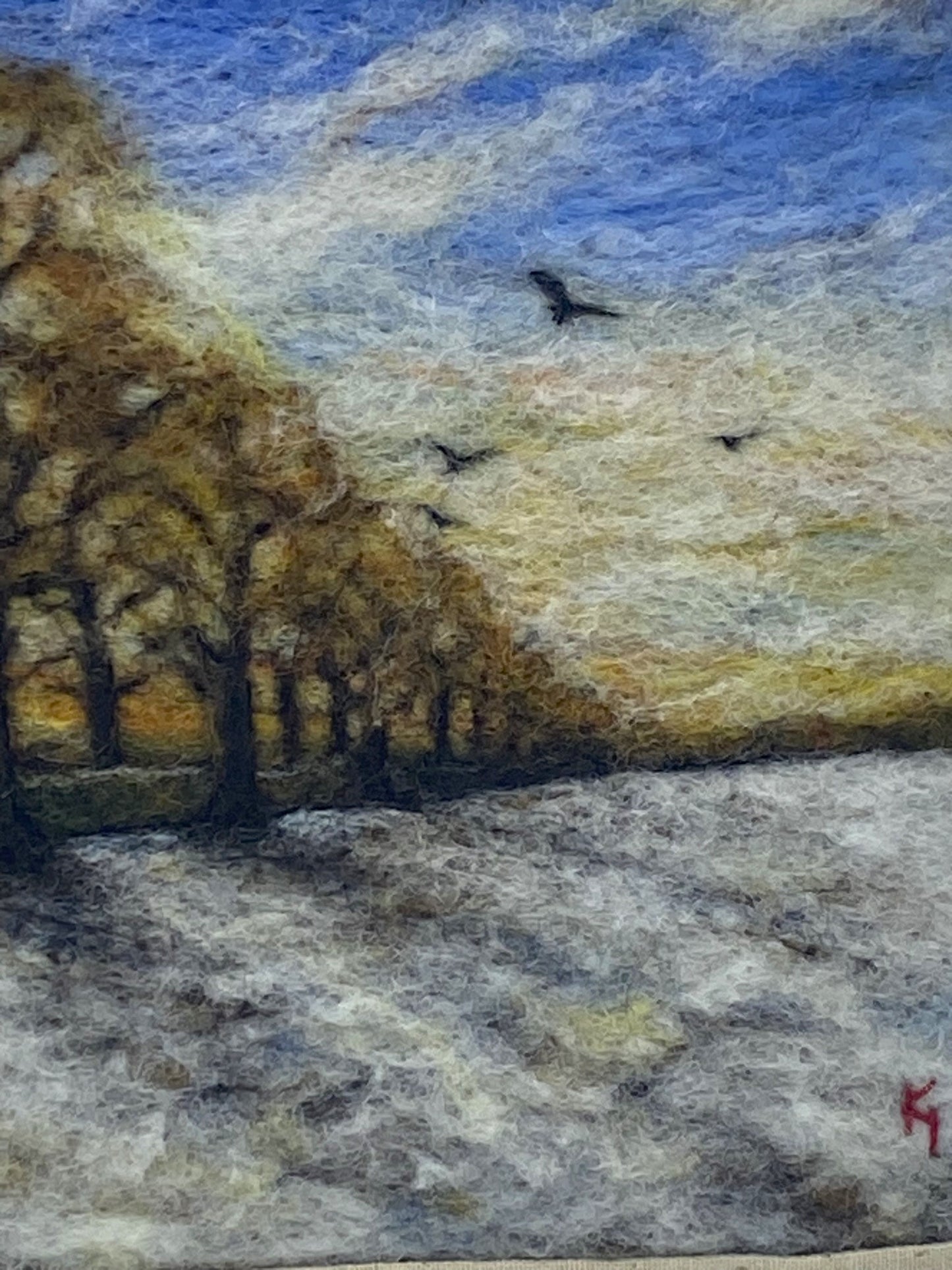 needle felted scene of a wintery sunrise with a row of almost bare trees following a lane to a distant horizon; the trees are casting shadows on a snowy field