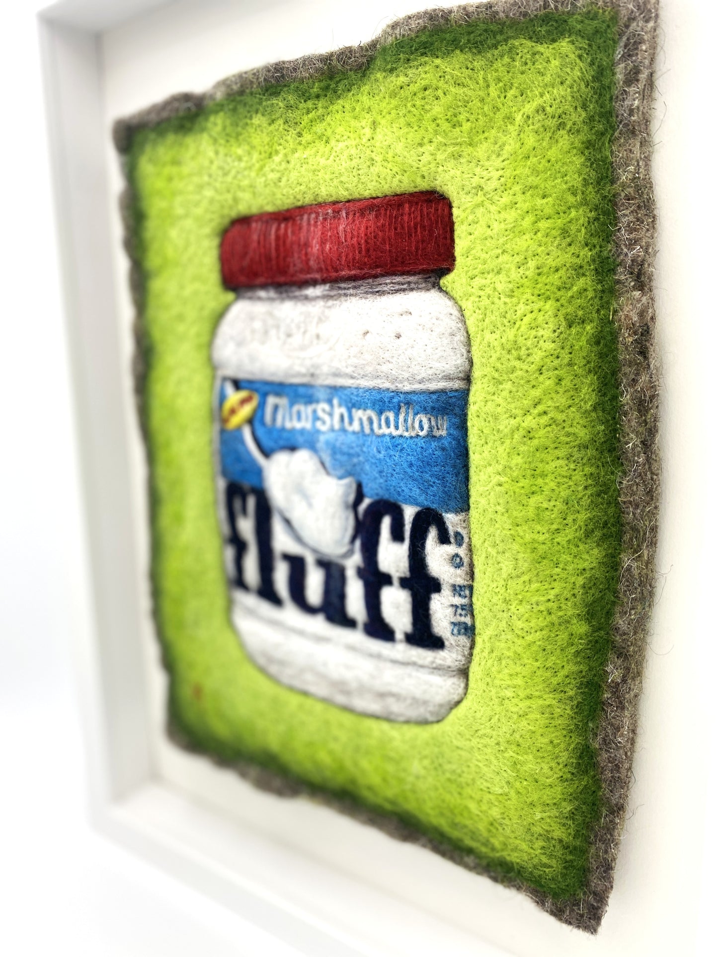 a needle felted picture of a jar of Fluff marshmallow spread, on a bright green background