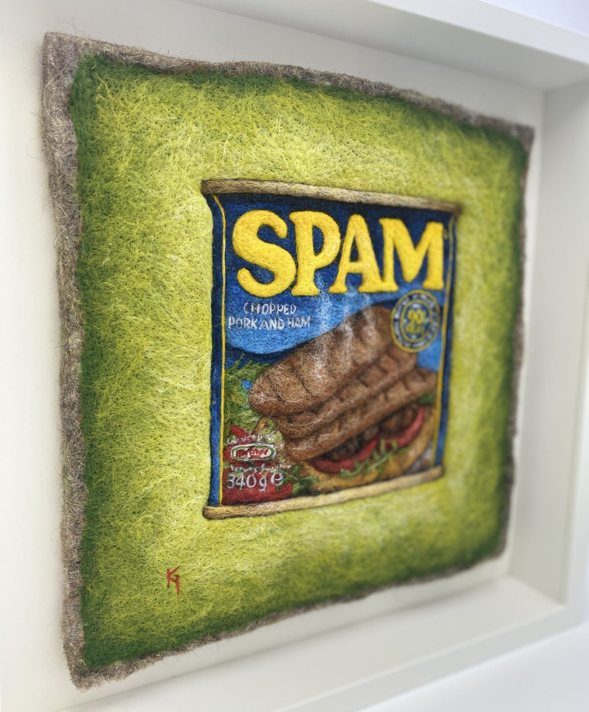 a needle felted picture of a can of Spam on a green background