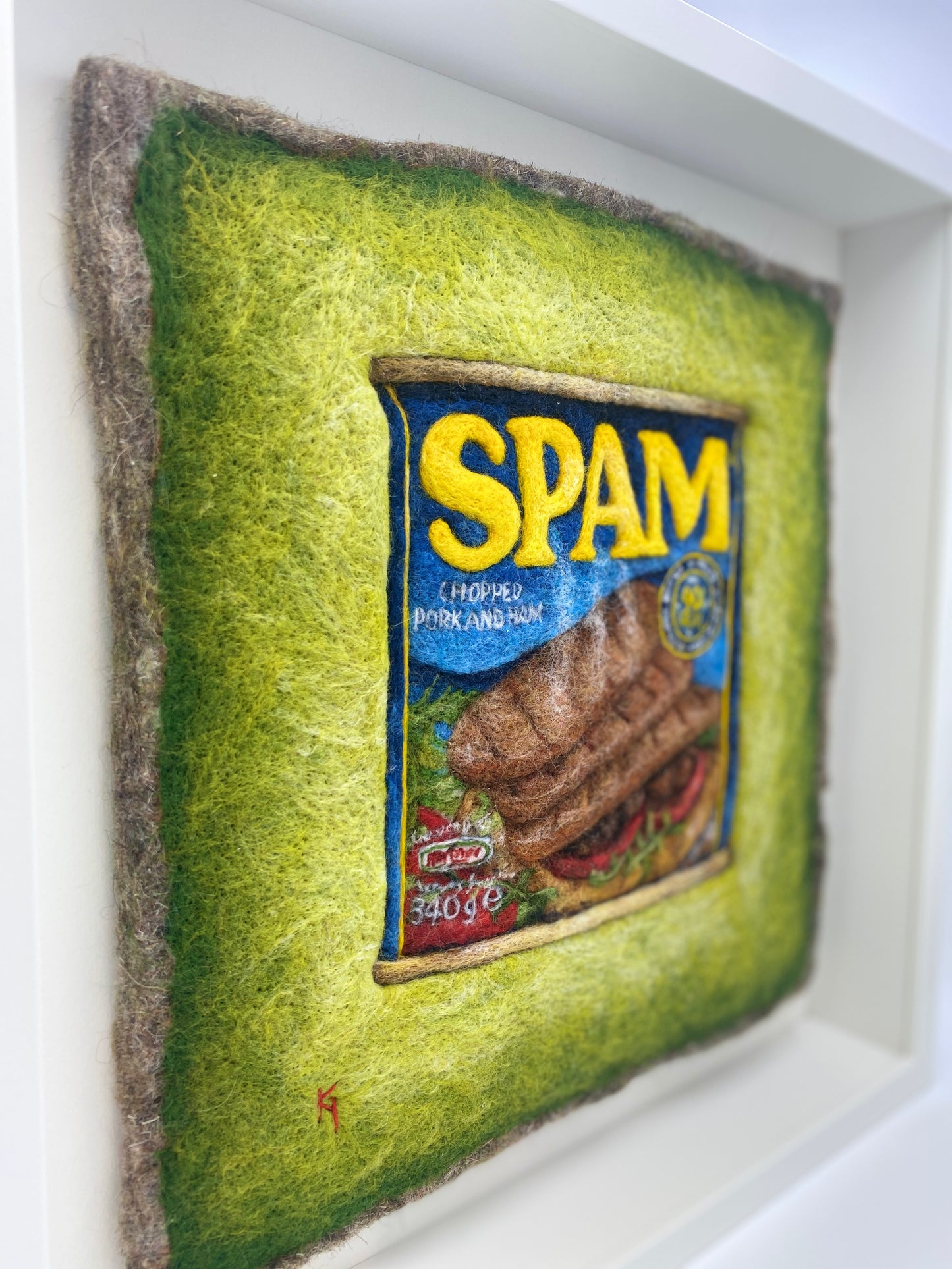 a needle felted picture of a can of Spam on a green background