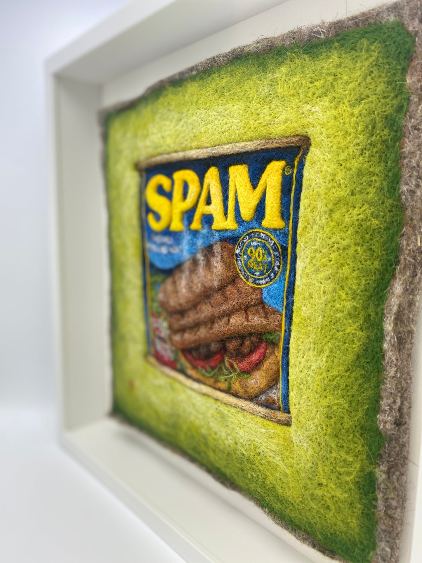 a needle felted picture of a can of Spam on a green background