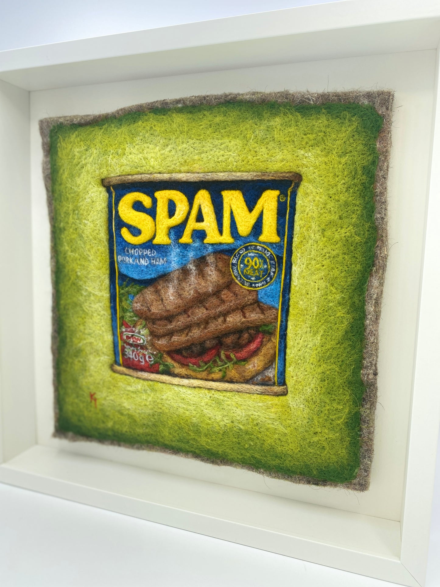 a needle felted picture of a can of Spam on a green background