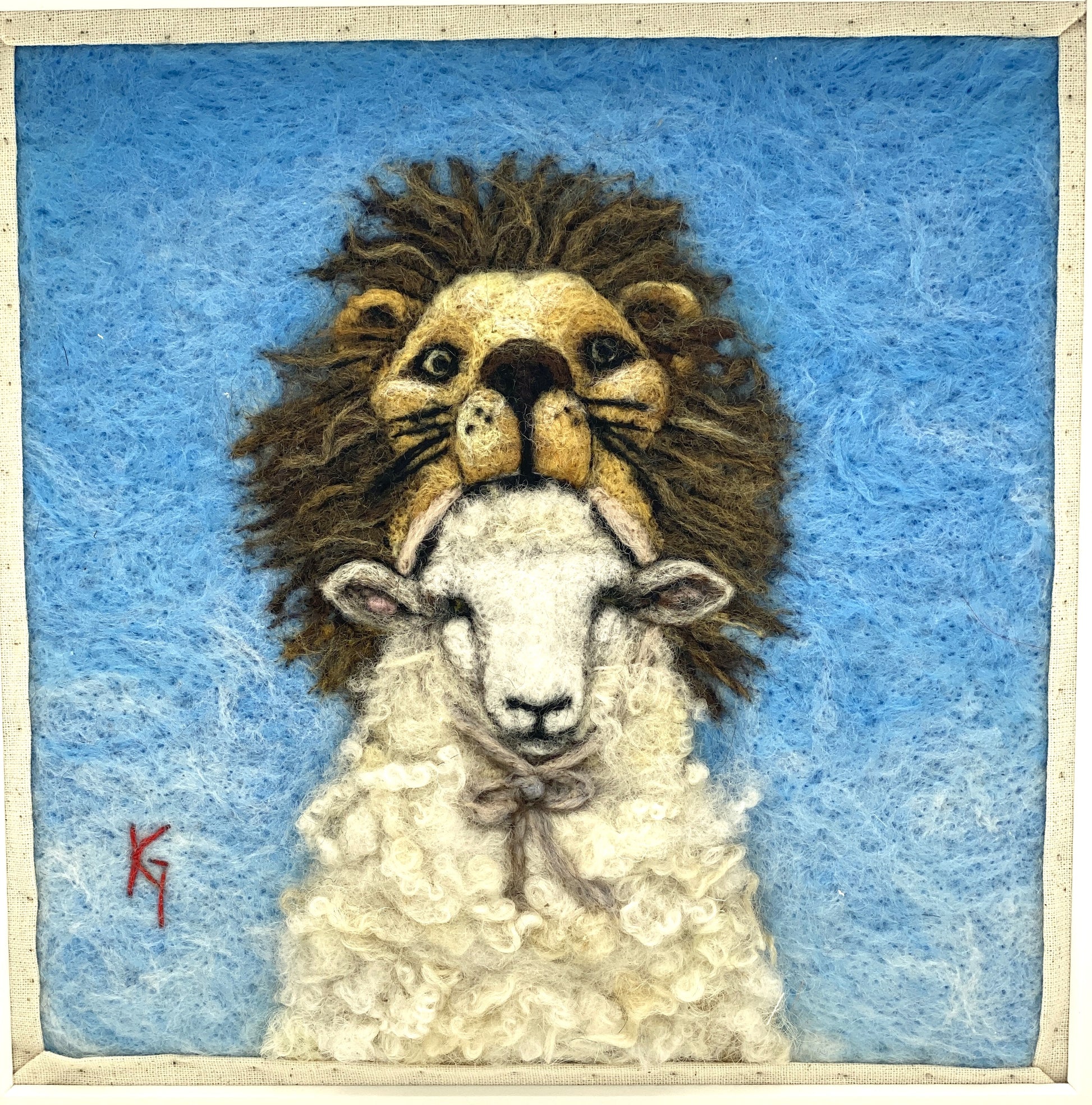 Needle felted framed depiction of a sheep with a lion headdress, with a blue background