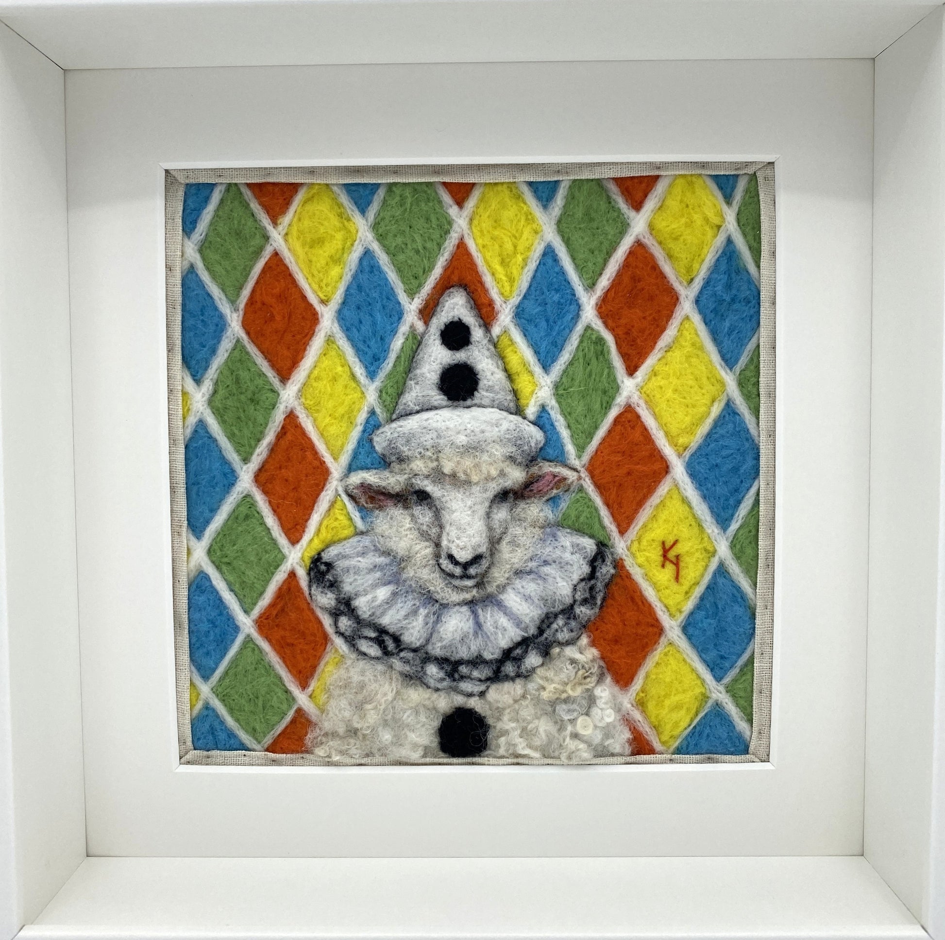 needle felted sheep dressed in Pierrot costume with harlequin background