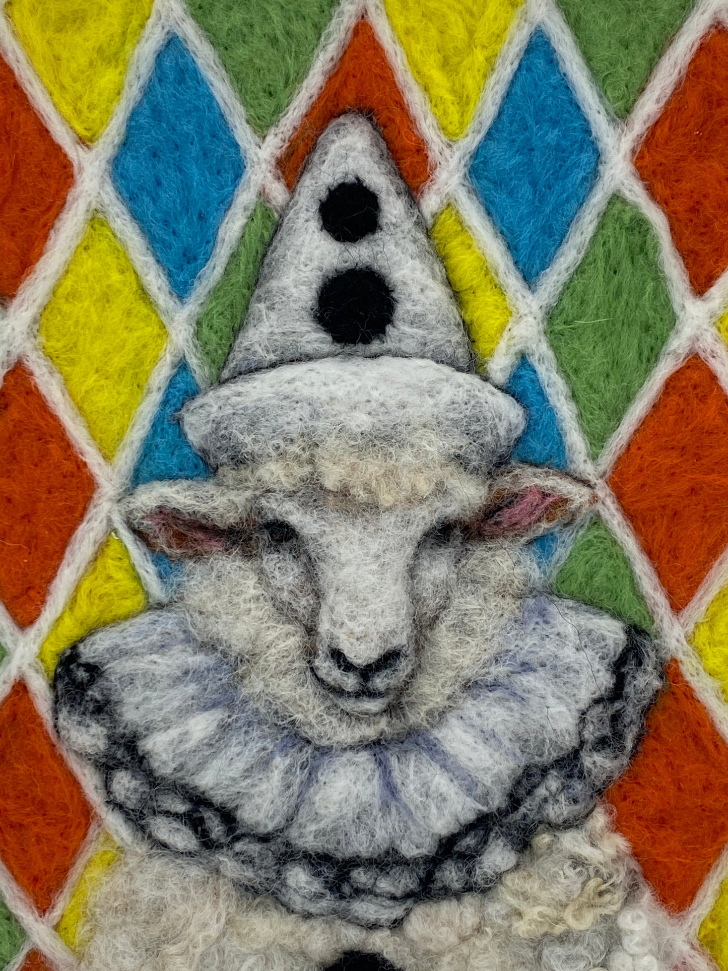 needle felted sheep dressed in Pierrot costume with harlequin background