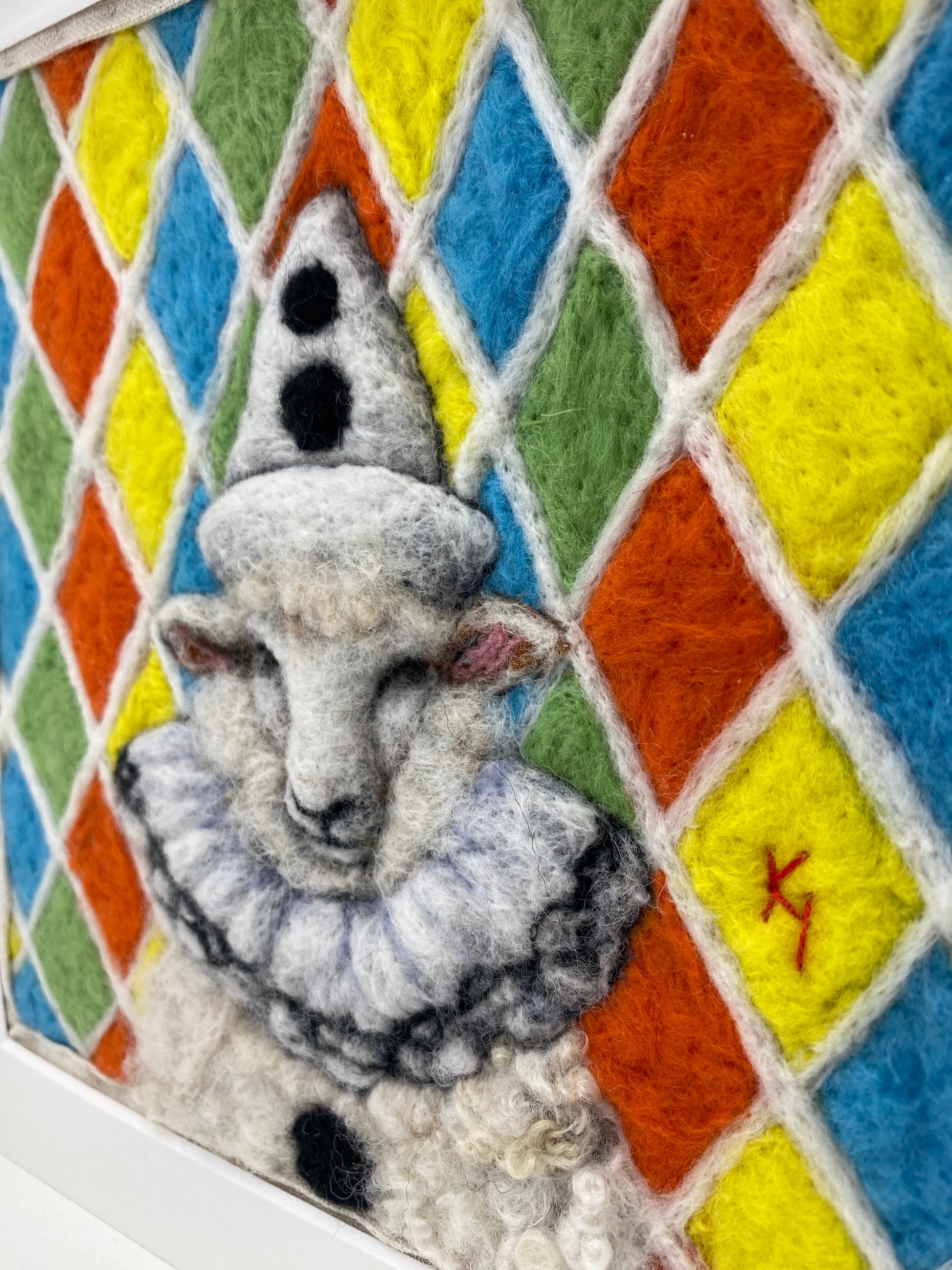 needle felted sheep dressed in Pierrot costume with harlequin background