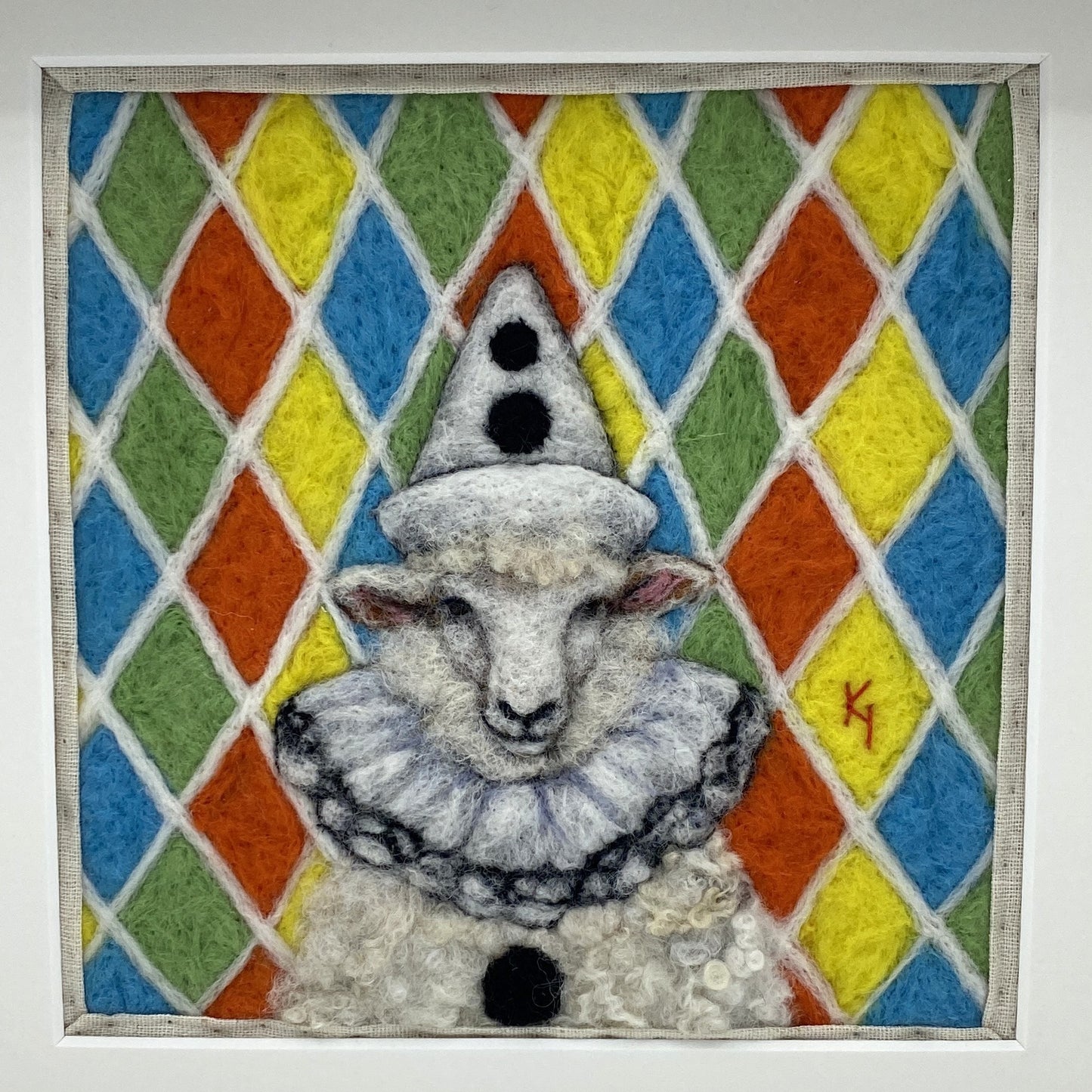needle felted sheep dressed in Pierrot costume with harlequin background