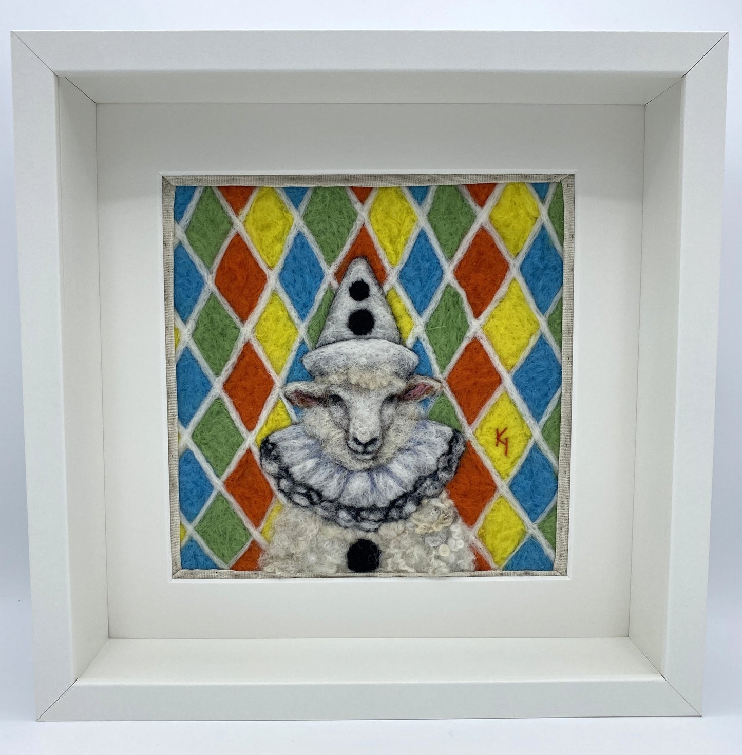 needle felted sheep dressed in Pierrot costume with harlequin background