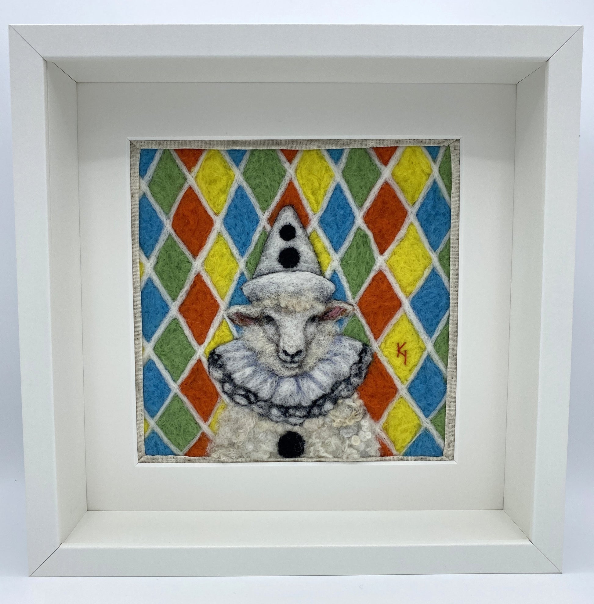 needle felted sheep dressed in Pierrot costume with harlequin background