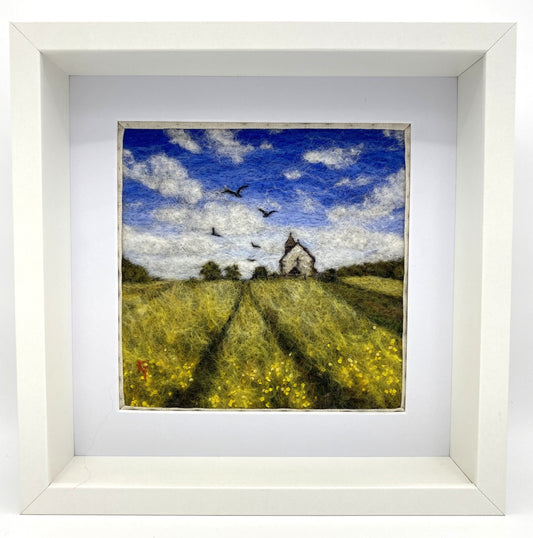 needle felted depiction of a church in a field with birds flying overhead in th cloudy blue sky
