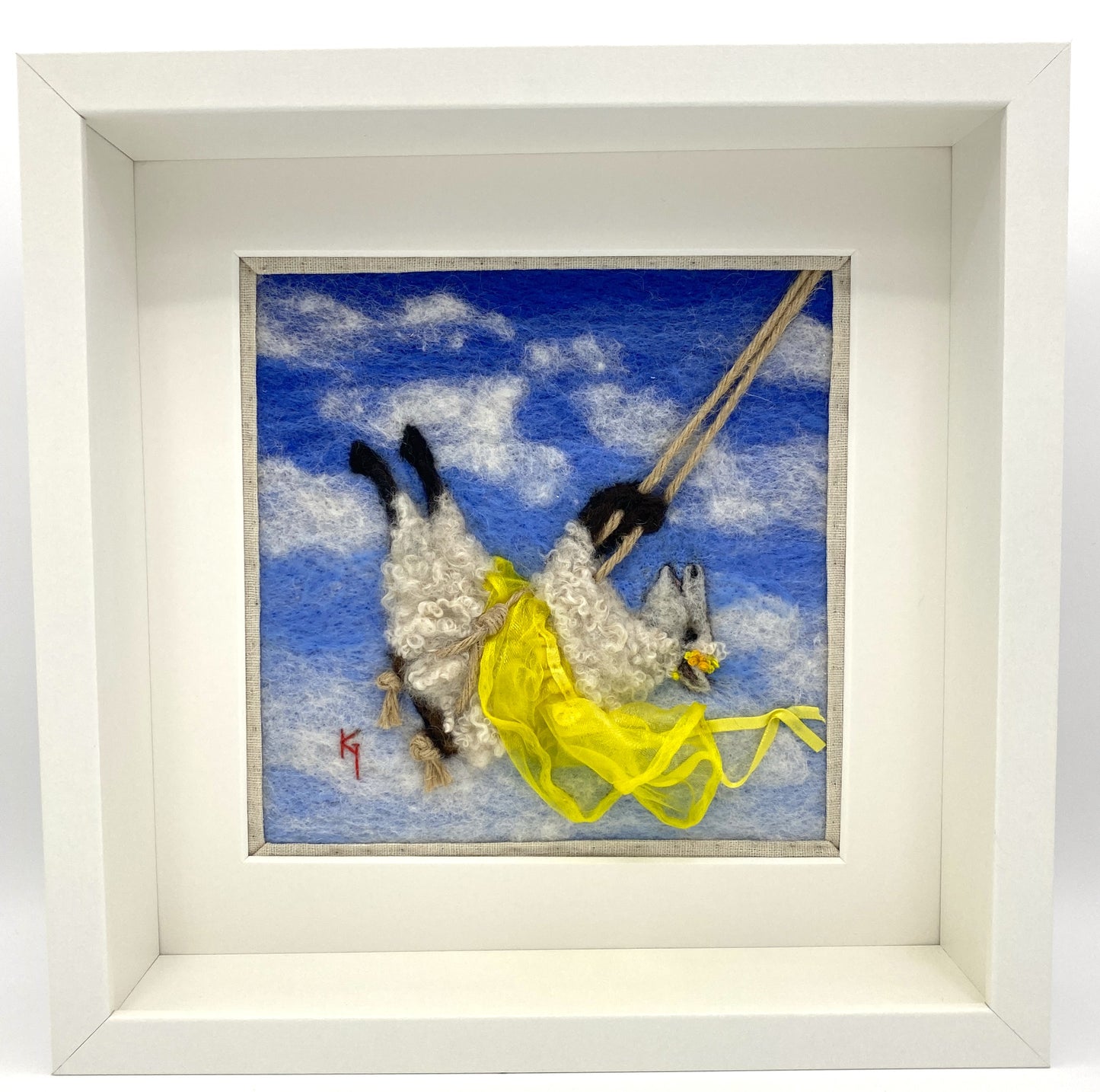 needle felted art work depicting a sheep on a swing wearing a yellow skirt