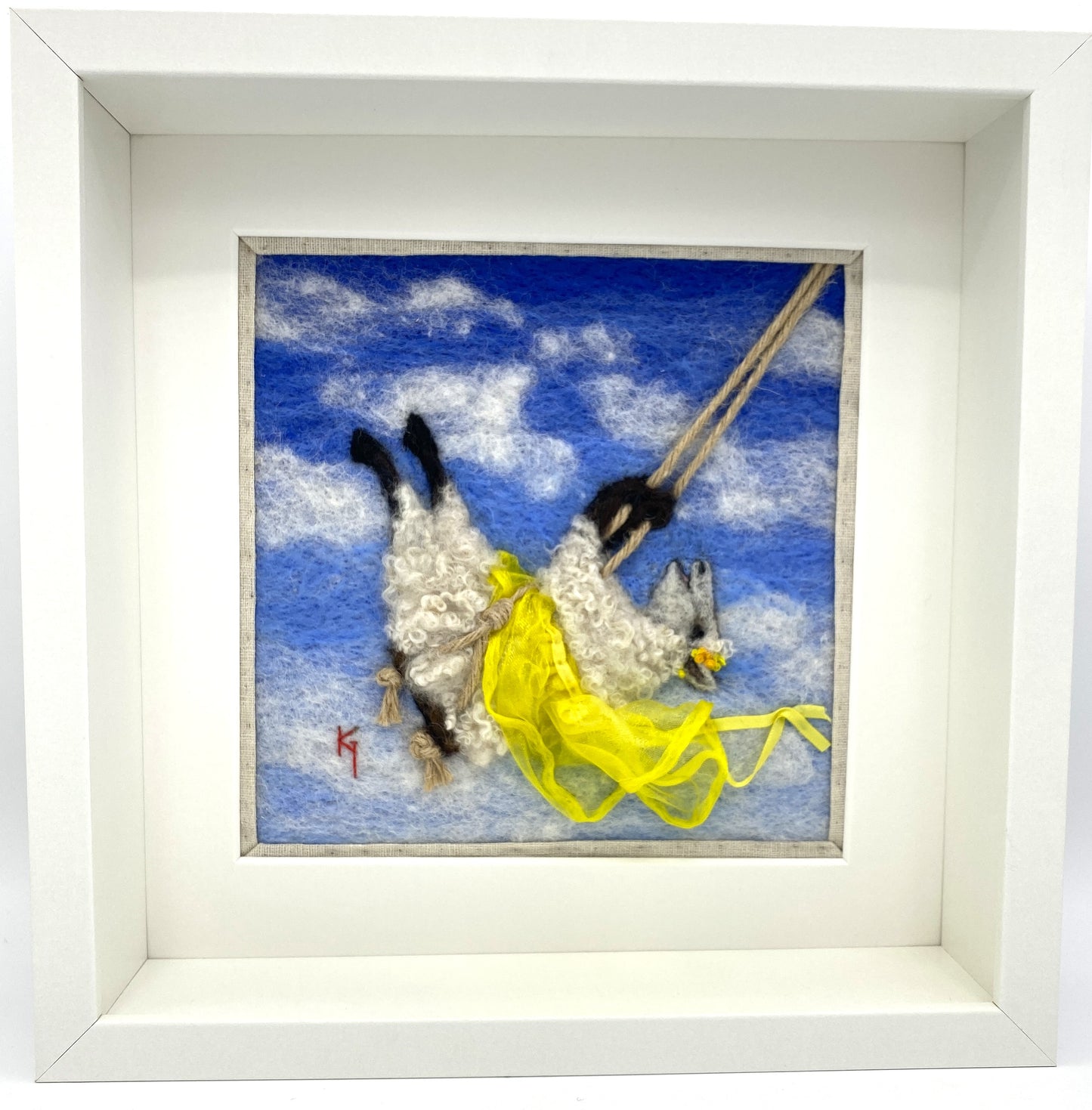 needle felted art work depicting a sheep on a swing wearing a yellow skirt