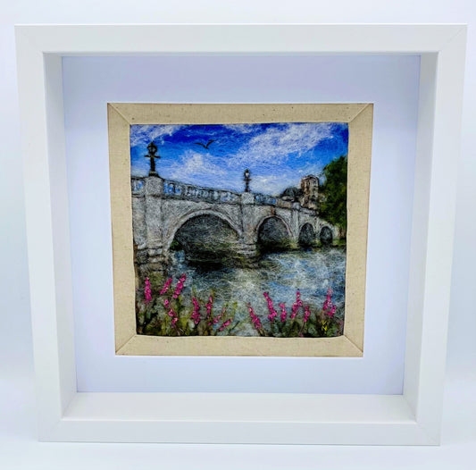 a box-framed, needle felted wool fibre picture of Ricmond Bridge showing the bridge, buildings across the river, trees, lamp posts and embroidered purple wild flowers