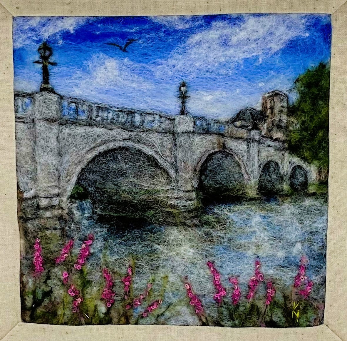 a box-framed, needle felted wool fibre picture of Ricmond Bridge showing the bridge, buildings across the river, trees, lamp posts and embroidered purple wild flowers