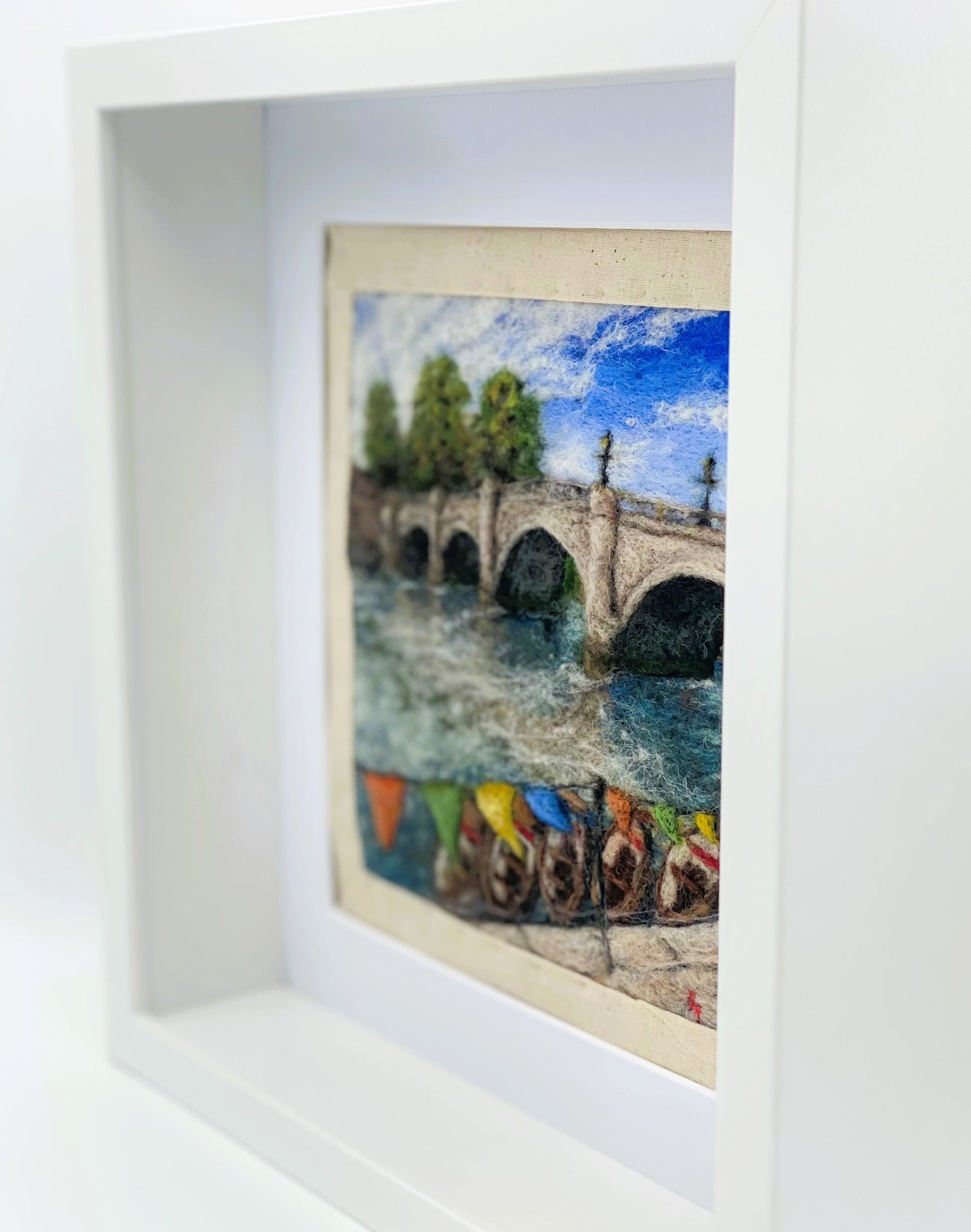 a box-framed, needle felted wool fibre picture of Ricmond Bridge showing the boats moared on the river, the bridge, trees, lamp posts and colourful bunting