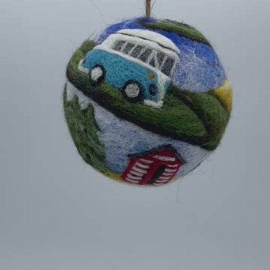 needle felted bauble depicting a camper van travelling through mountains, camping site and countryside and finally reaching the beach hut by the sea