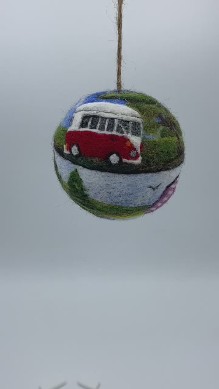 needle felted bauble depicting a camper van travelling through mountains, camping site and countryside and finally reaching the beach hut by the sea