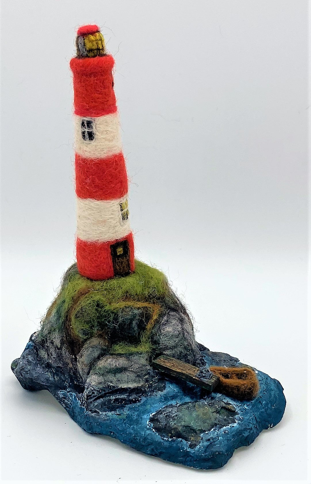 needle felted lighthouse, rocks, boat, jetty, path to front door, sea, grass, painted waves, on oyster shell base 